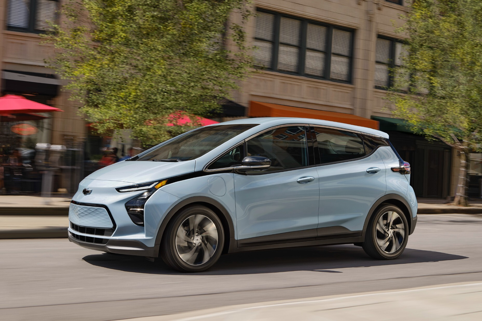 Light blue Chevrolet electric SUV parked on urban street with ivy-covered building facade