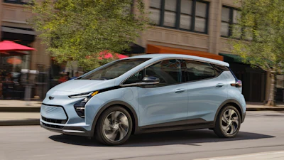 Light blue Chevrolet electric SUV parked on urban street with ivy-covered building facade