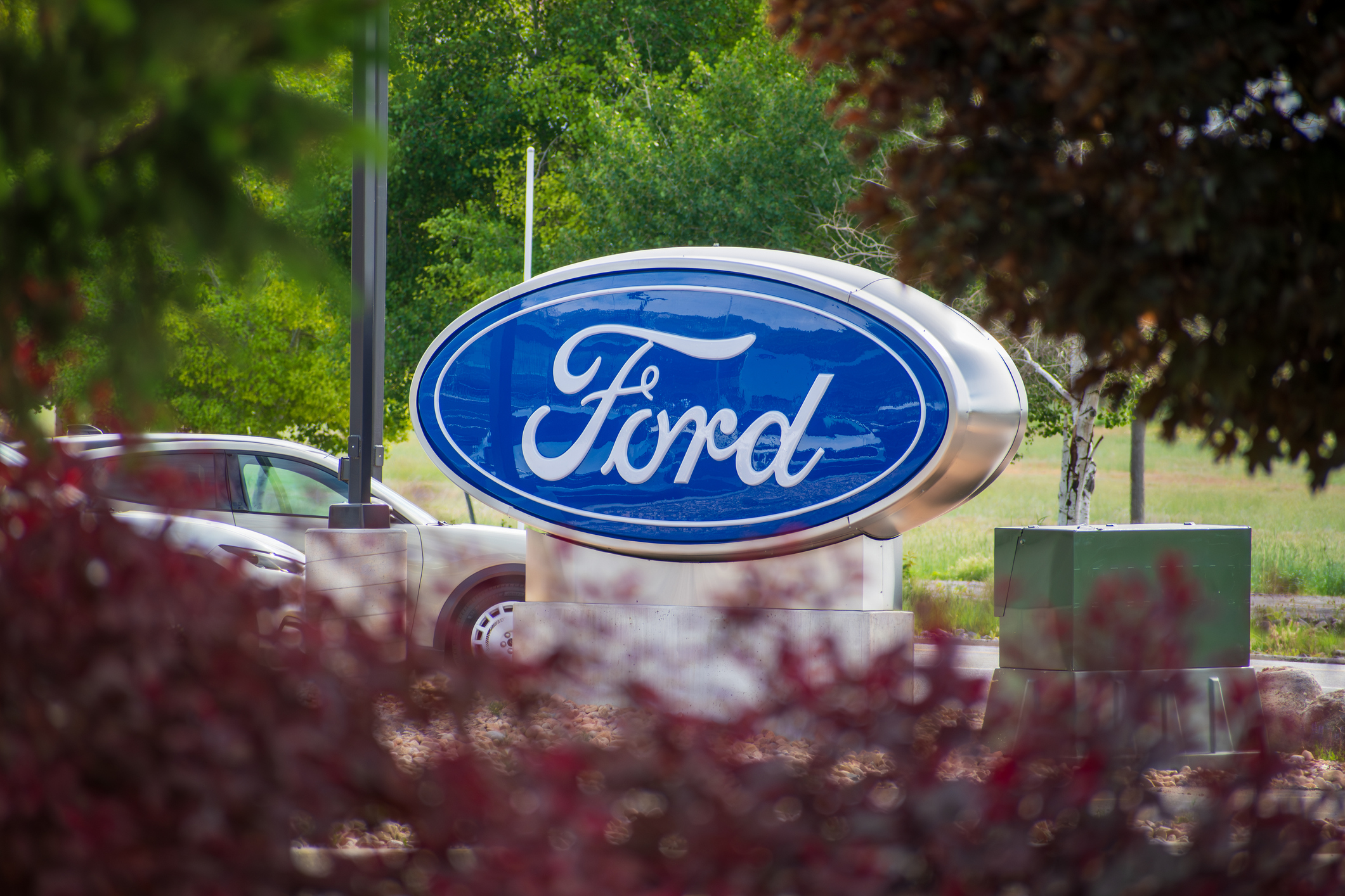 Ford logo sign displayed on a monument with landscaping and trees in background