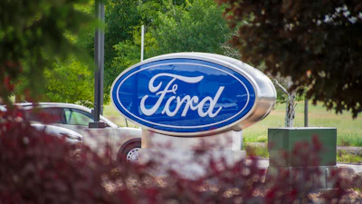 Ford logo sign displayed on a monument with landscaping and trees in background
