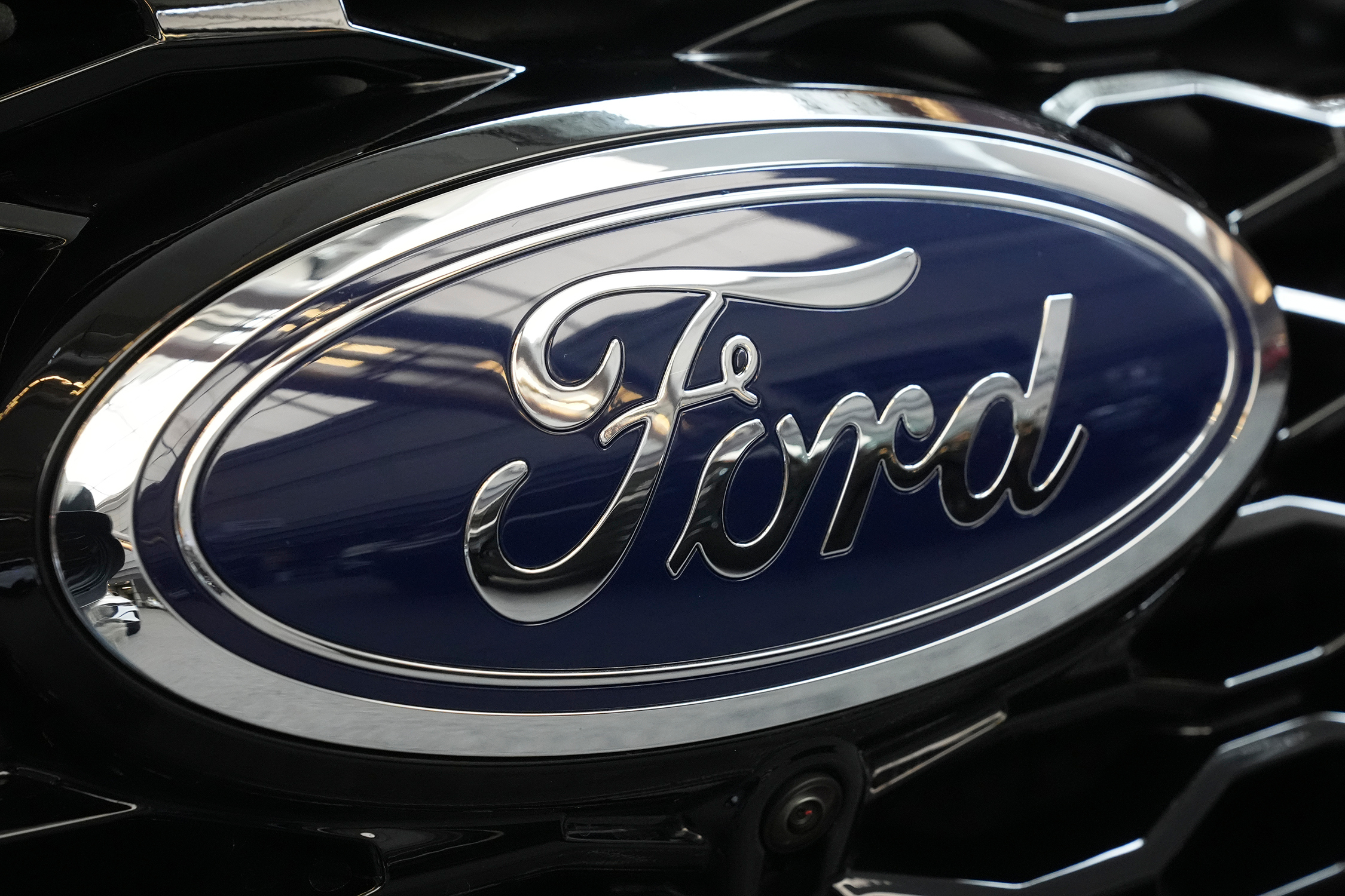 Ford logo emblem on vehicle hood with dark blue background and chrome trim