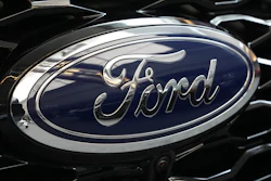 Ford logo emblem on vehicle hood with dark blue background and chrome trim