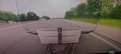 Dashboard camera view of a highway with multiple lanes, trees on both sides, and vehicles in the distance