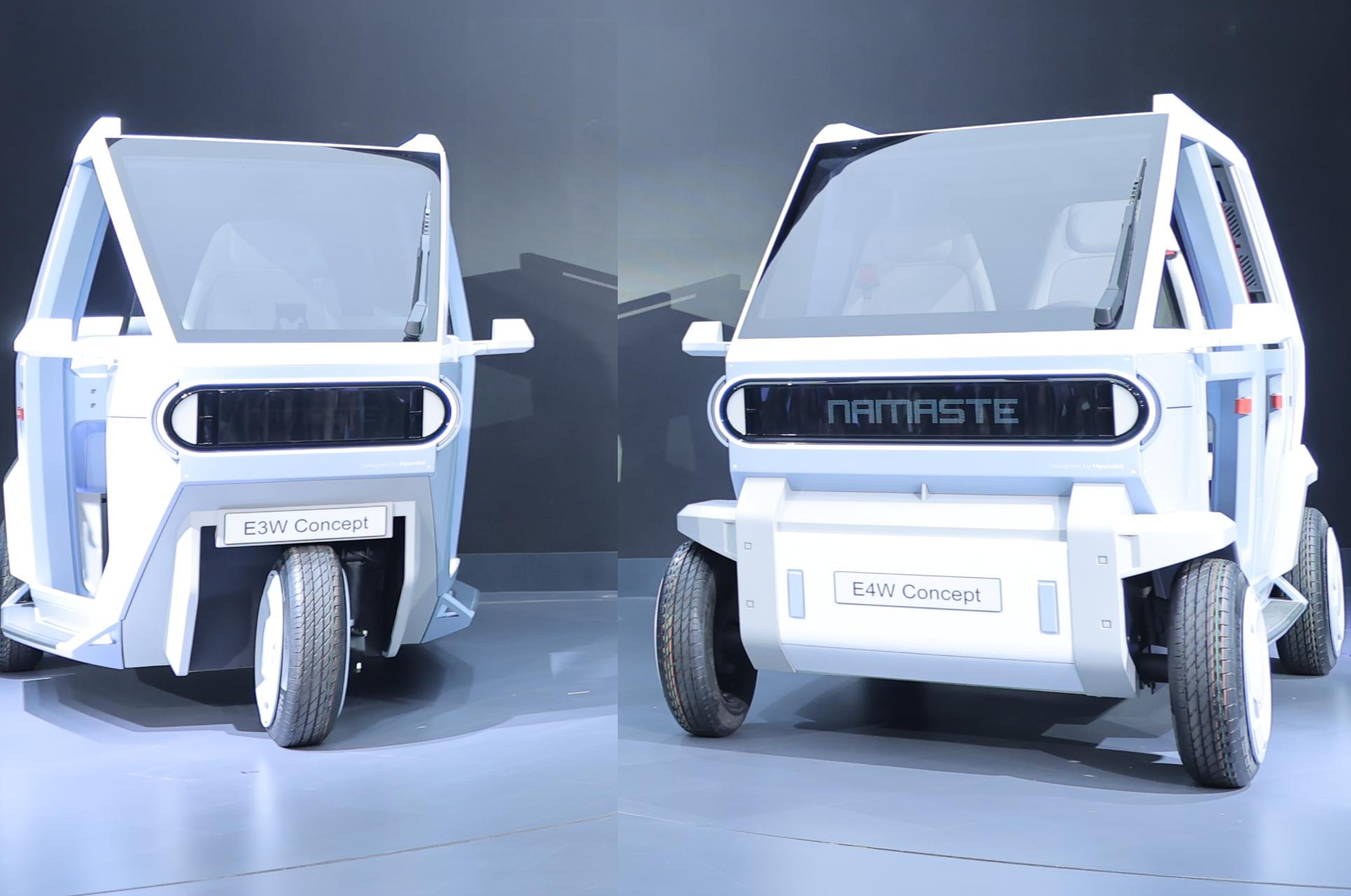 Two white E4W Concept electric vehicles displayed side-by-side with open doors in a modern showroom