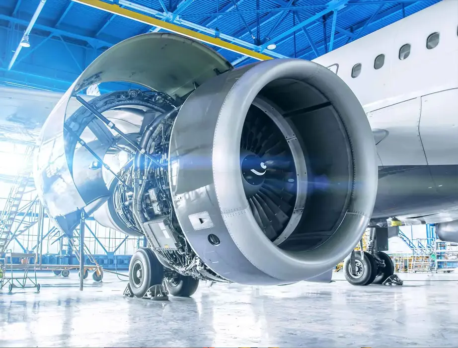 Aircraft engine maintenance in industrial hangar with exposed turbine components and scaffolding