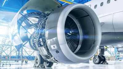 Aircraft engine maintenance in industrial hangar with exposed turbine components and scaffolding