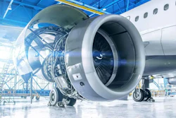 Aircraft engine maintenance in industrial hangar with exposed turbine components and scaffolding