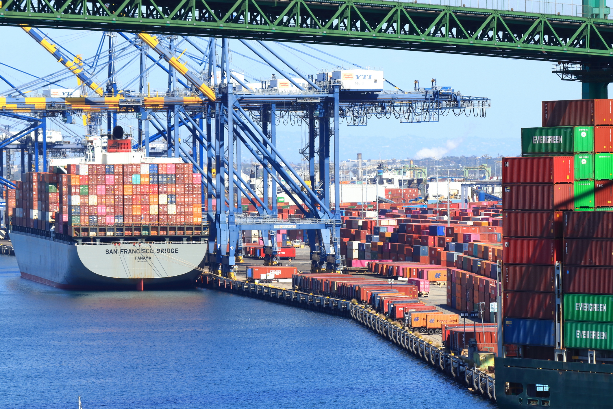 Container ship docked at busy port terminal with stacked cargo containers and loading cranes