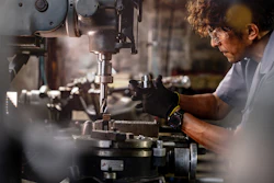 Skilled machinist operating precision metal cutting equipment in industrial workshop setting