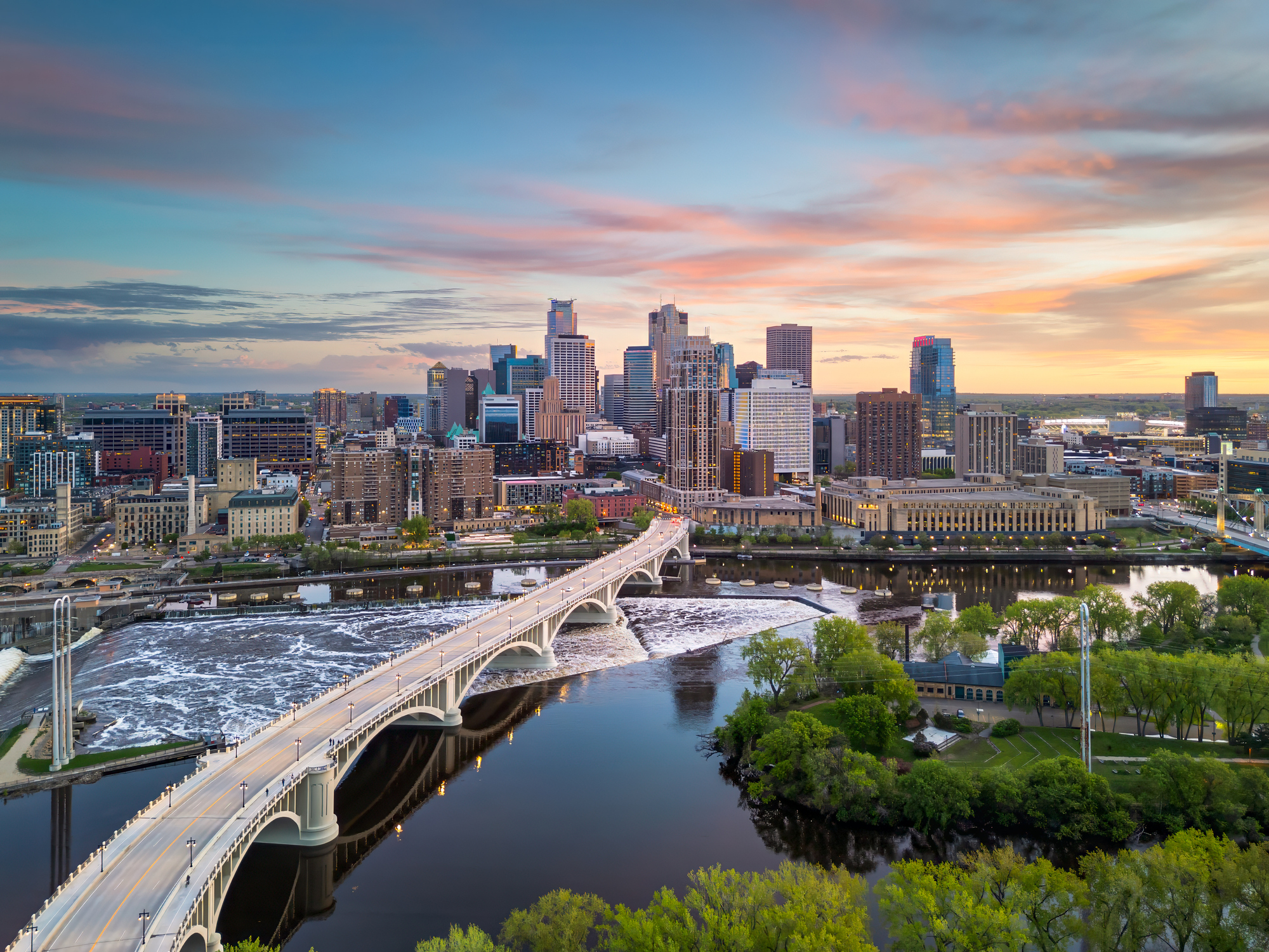 Minneapolis skyline at sunset with Stone Arch Bridge spanning the Mississippi River