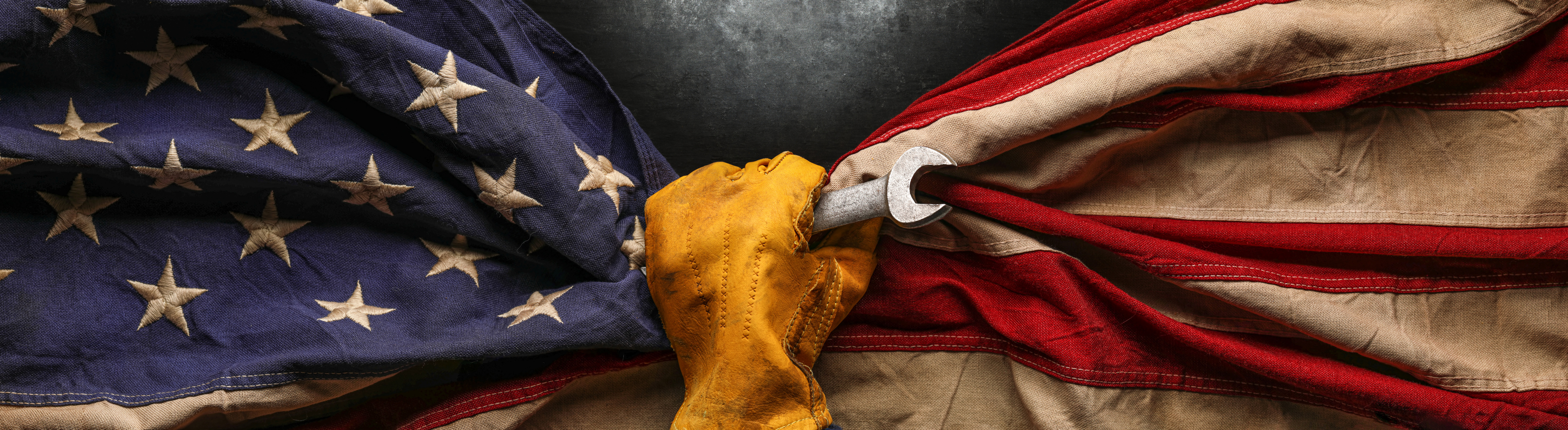 Hand holding folded American flag with yellow cloth against dark background