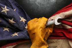 Hand holding folded American flag with yellow cloth against dark background