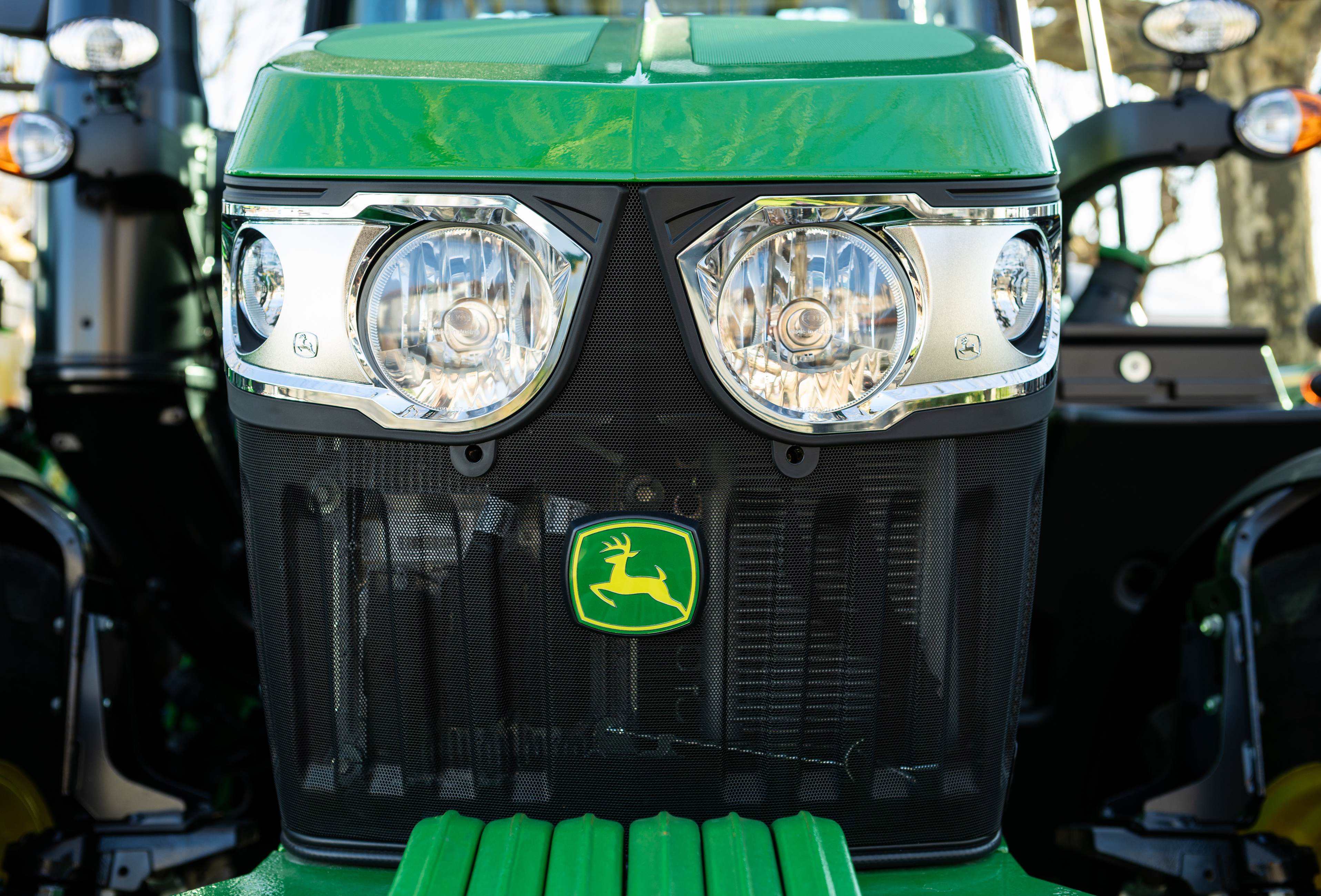 Green John Deere tractor front view with dual headlights and yellow deer logo