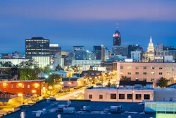 Urban skyline at twilight with illuminated buildings, street lights, and capitol dome in background