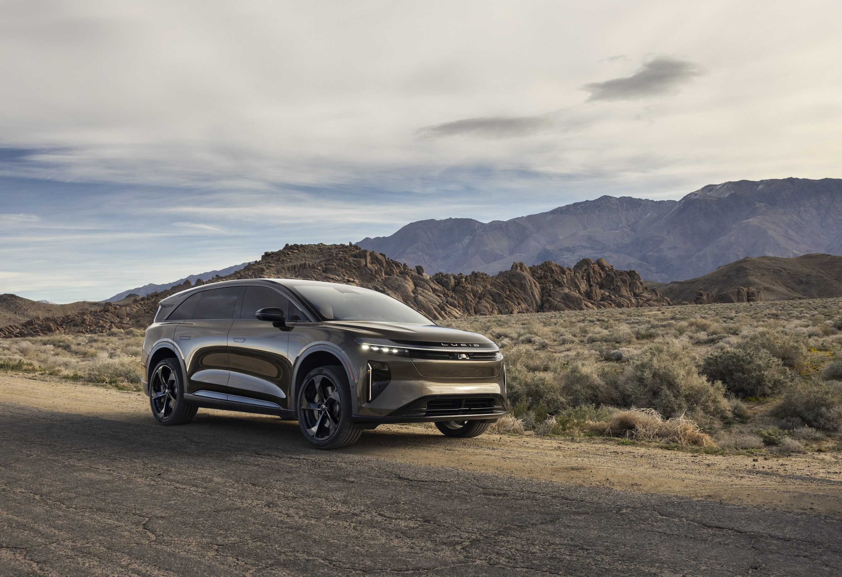 Silver Cadillac Lyriq electric SUV parked in desert landscape with rocky mountains