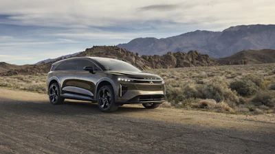 Silver Cadillac Lyriq electric SUV parked in desert landscape with rocky mountains