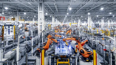 Modern automotive manufacturing facility with orange robotic arms assembling vehicles on production line