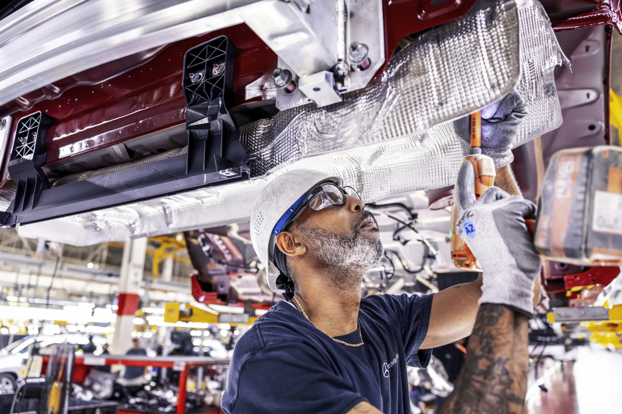 Automotive technician assembling vehicle component in manufacturing facility
