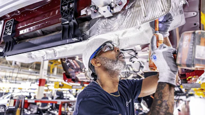 Automotive technician assembling vehicle component in manufacturing facility