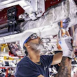 Automotive technician assembling vehicle component in manufacturing facility