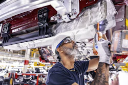 Automotive technician assembling vehicle component in manufacturing facility