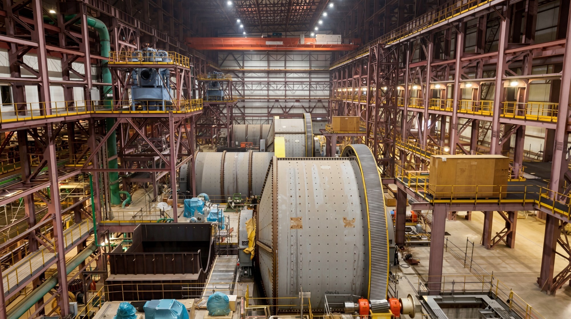 Industrial aerospace manufacturing facility with large cylindrical spacecraft components and overhead cranes in assembly bay