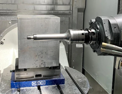 Industrial CNC machine with metal workpiece mounted on spindle during precision machining operation