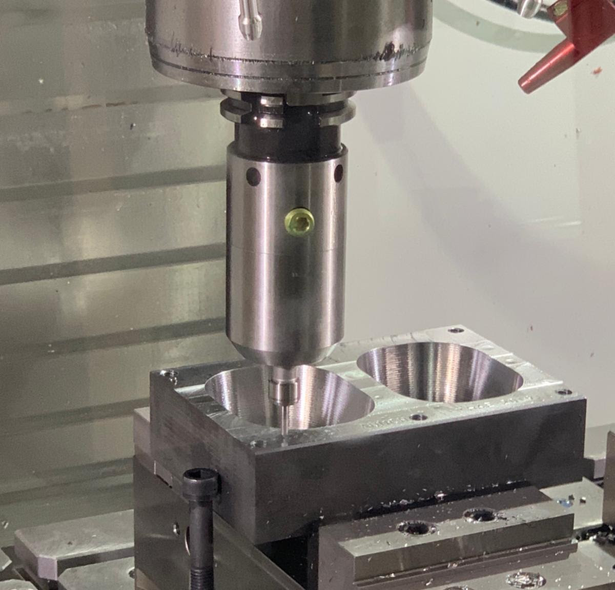 CNC press machine with cylindrical punch tool positioned above metal workpiece with two circular cavities