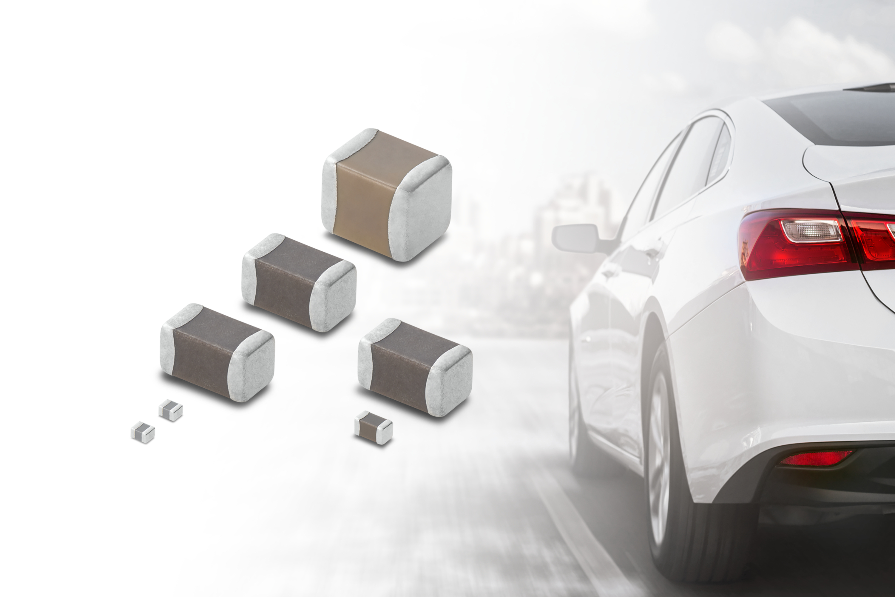 Various SMD electronic components and capacitors displayed next to a white car's rear quarter panel