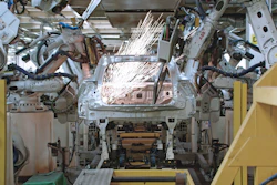 Robotic welding arms performing assembly on vehicle body in automotive manufacturing facility