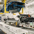 Blue car body suspended on assembly line with engine and chassis components during manufacturing