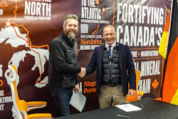 Two men shake hands at a mining industry trade show with Norderra and Niagara Ports branding visible in background.