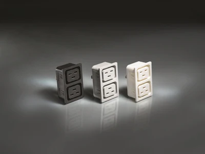 Three electrical outlet designs in black, white, and beige with dual socket configurations displayed on reflective surface