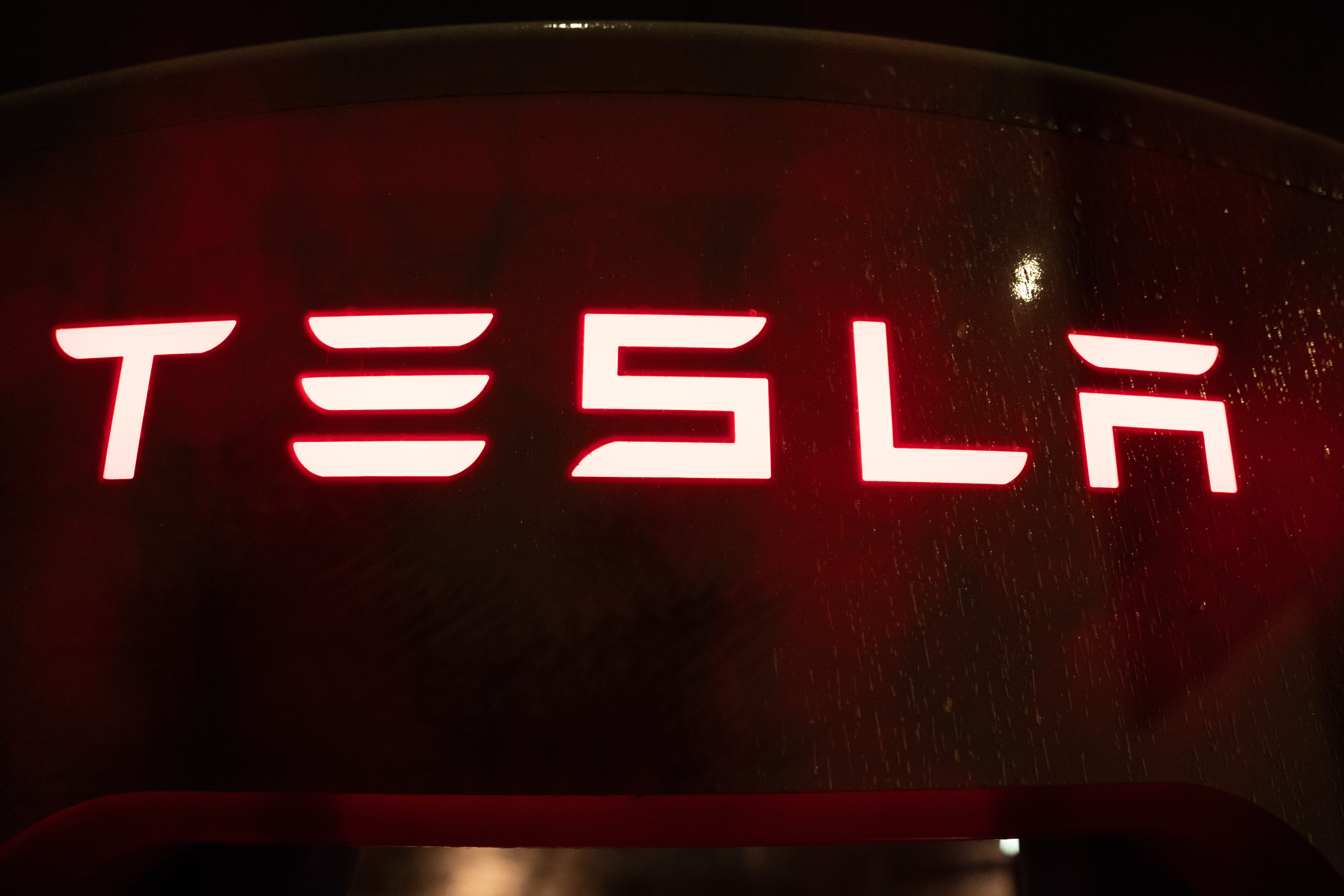 Tesla neon sign glowing red and white against dark background