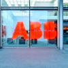 ABB red logo signage on glass storefront with urban street and pedestrians