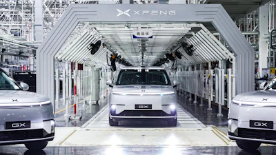 XPENG electric vehicles on assembly line in modern manufacturing facility with white industrial architecture