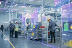 Modern factory floor with workers monitoring machinery and digital performance metrics displayed on transparent screens