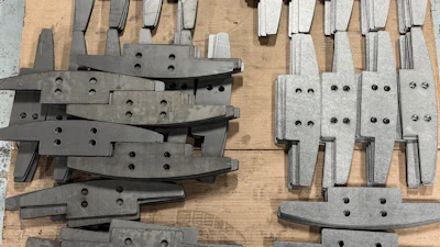 Assorted metal industrial parts with bolt holes arranged on wooden surface