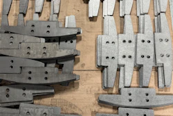 Assorted metal industrial parts with bolt holes arranged on wooden surface