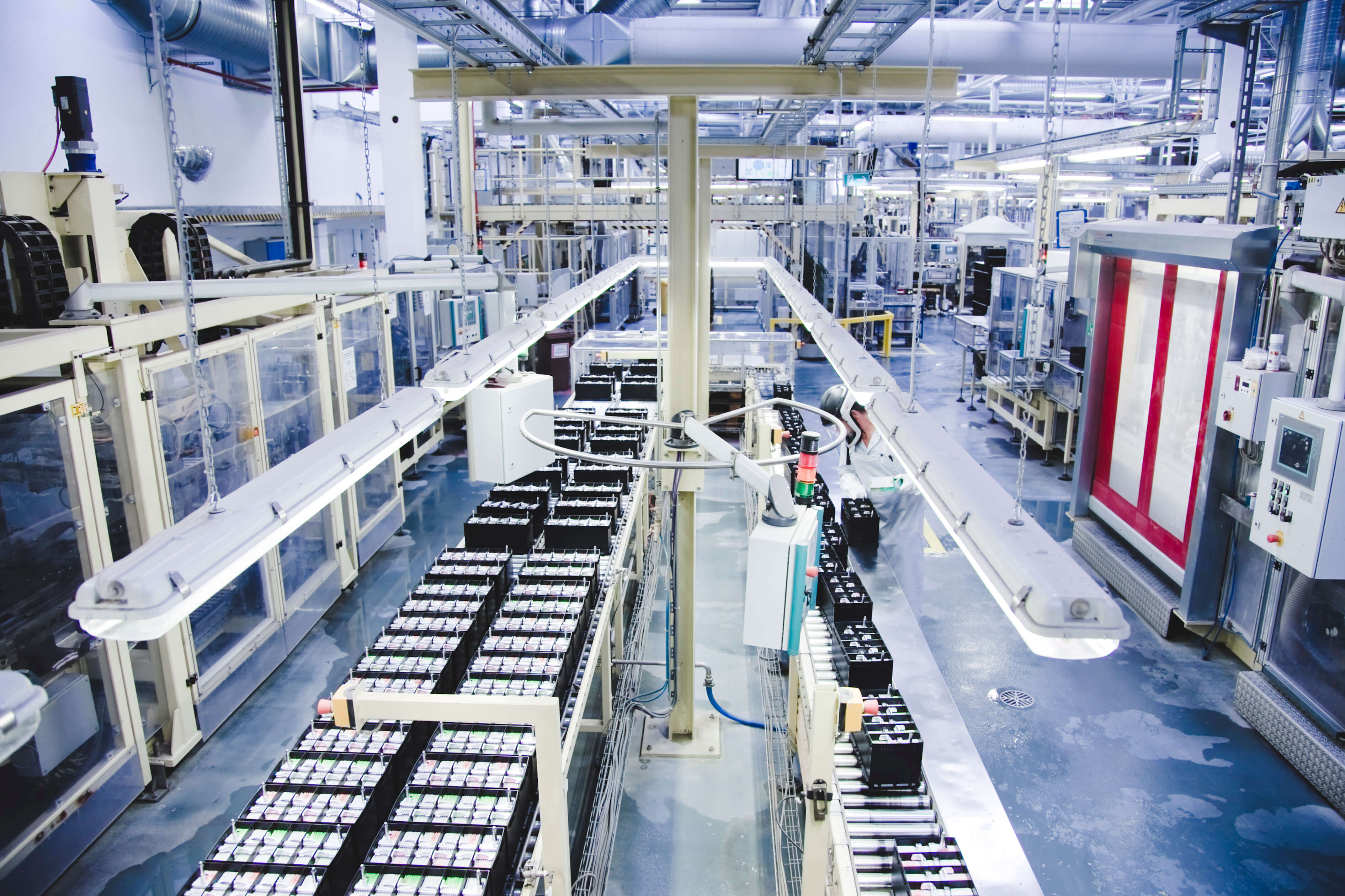 Industrial manufacturing facility with automated production lines, machinery, and storage systems in a modern factory warehouse.