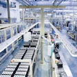 Industrial manufacturing facility with automated production lines, machinery, and storage systems in a modern factory warehouse.