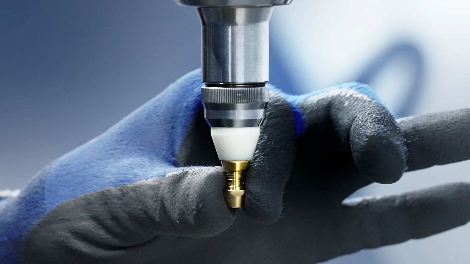 Plumber holding a brass pipe fitting with wrench and blue work gloves