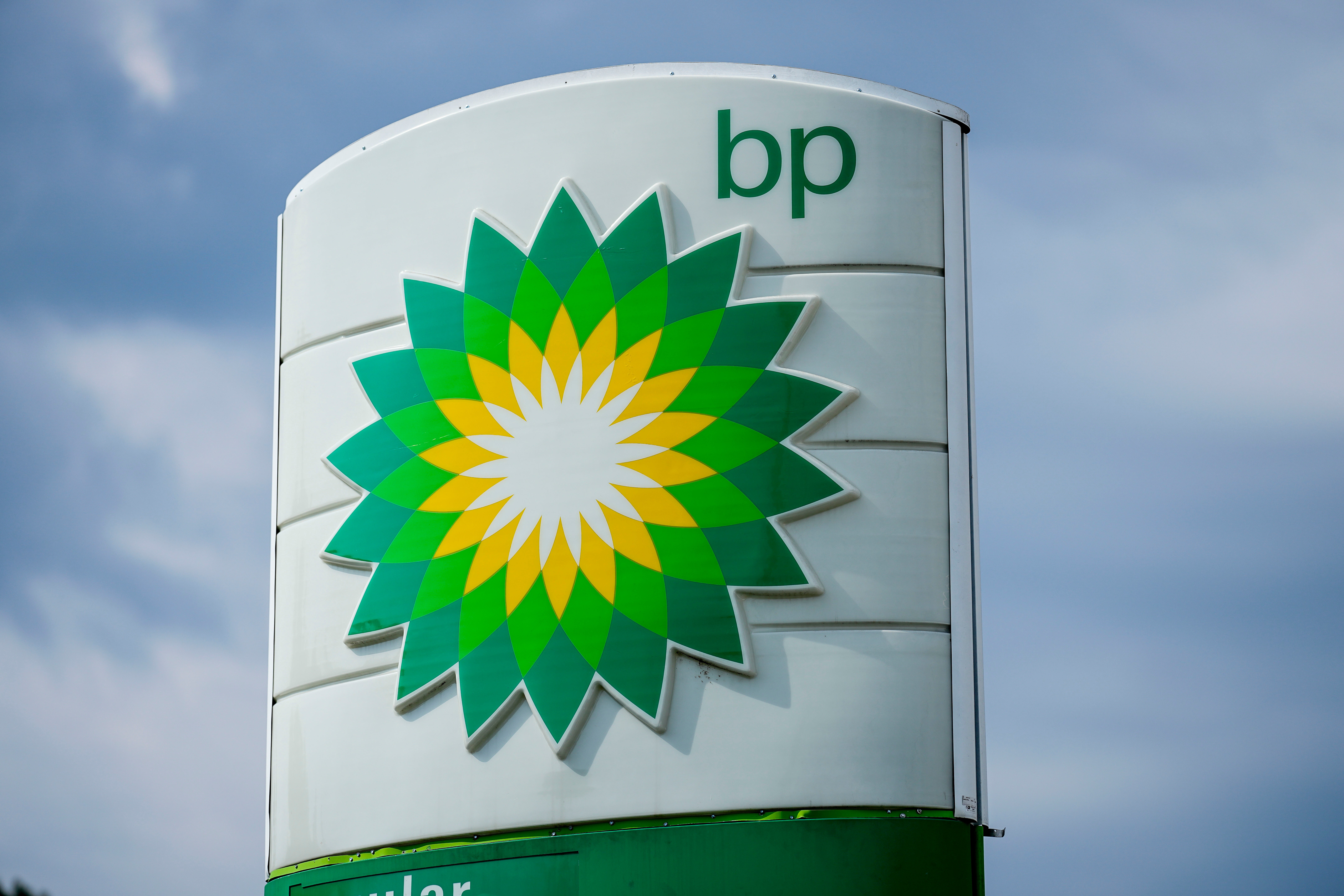 BP gas station sign with green and yellow sunburst logo against blue sky