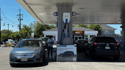 Chevron gas station with self-service fuel pumps and parked vehicles under blue canopy
