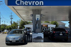 Chevron gas station with self-service fuel pumps and parked vehicles under blue canopy