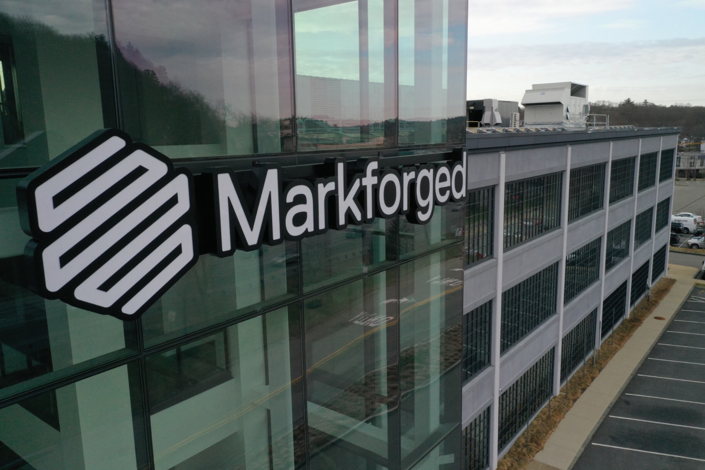 Markforged logo displayed on modern glass building exterior with parking lot visible