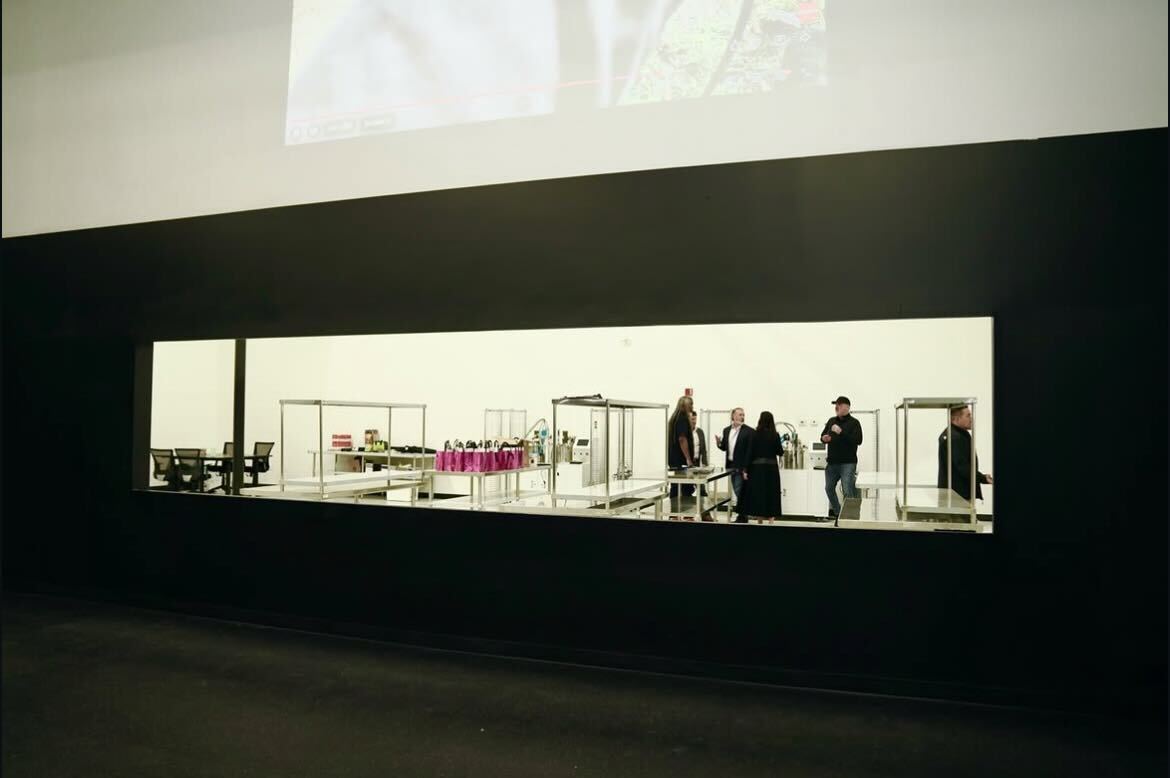 Modern architectural display window showing interior design installation with visitors observing contemporary furniture and design elements
