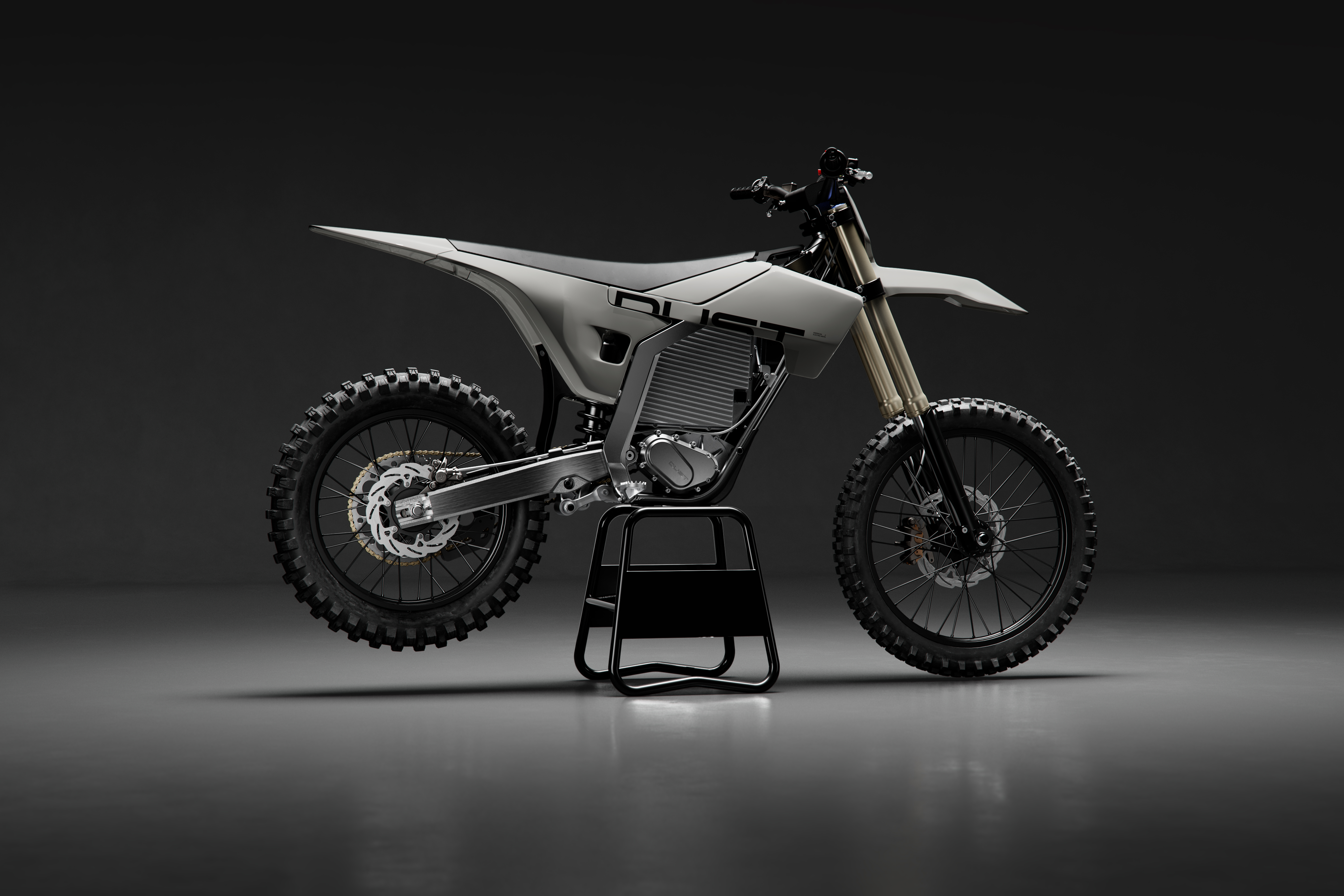 Modern electric dirt bike with white bodywork and dual disc brakes displayed on black stand