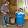 Technician operating a blue Chip Trapper dust collection system in a workshop setting