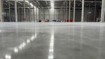 Spacious industrial warehouse with polished concrete floor, metal framework, and glass partitions